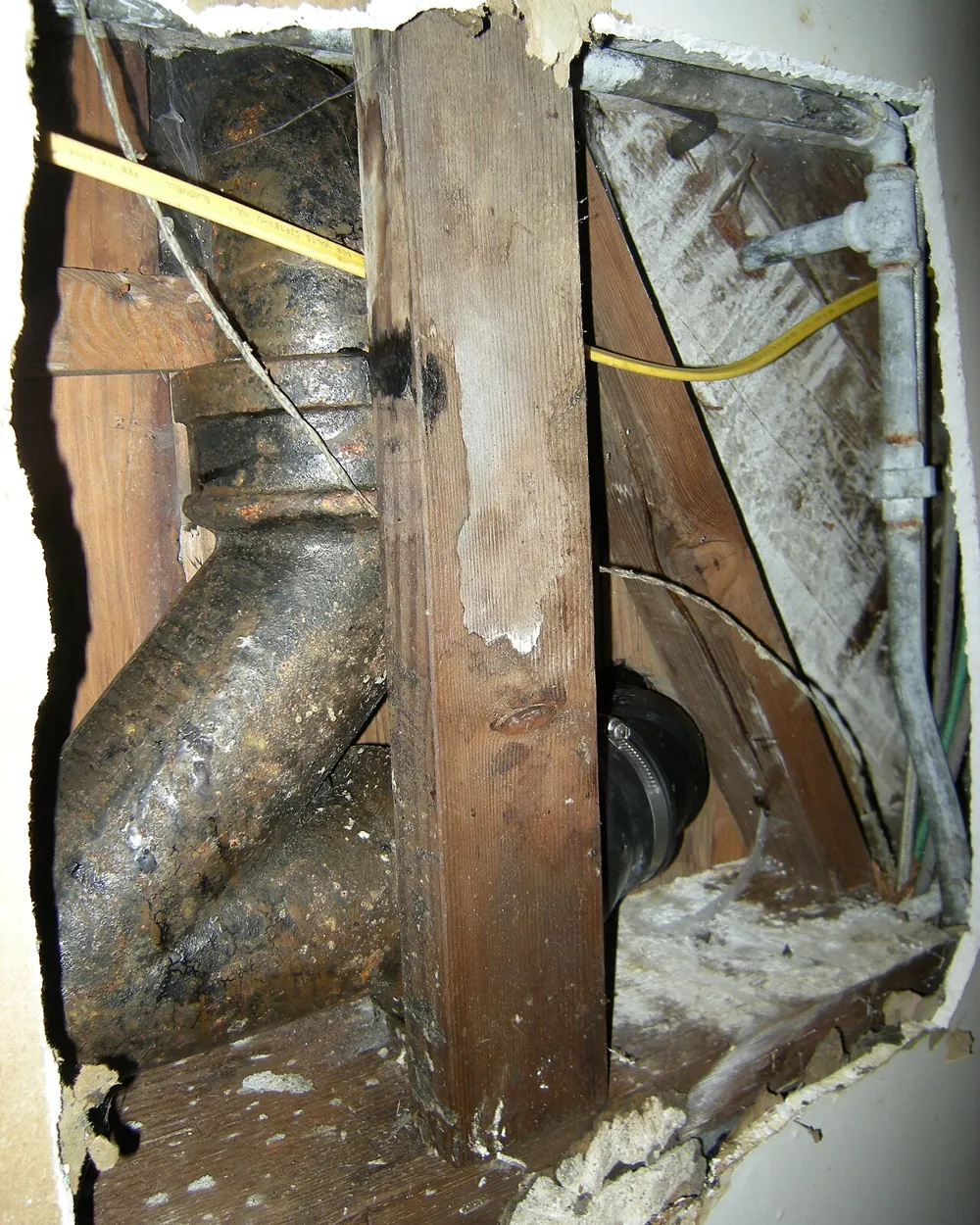 Old cast iron drain pipe exposed inside an opened wall