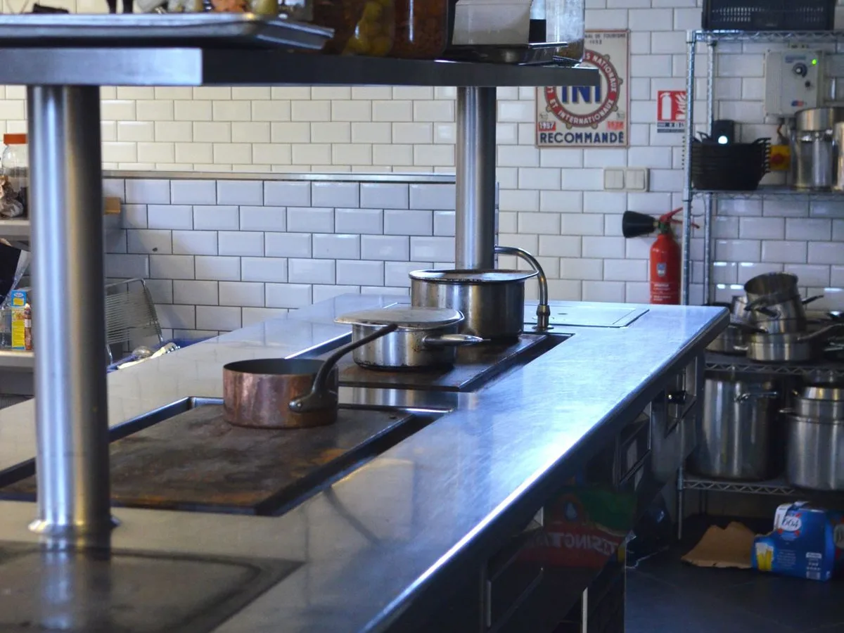 Commercial kitchen line with stainless steel counters and cookware