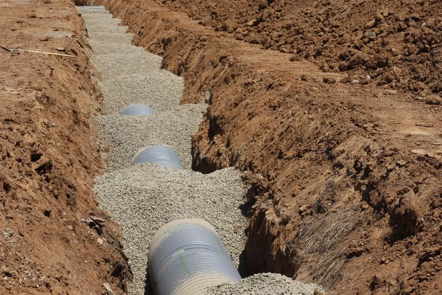 Large pipe being set in a gravel bedded trench